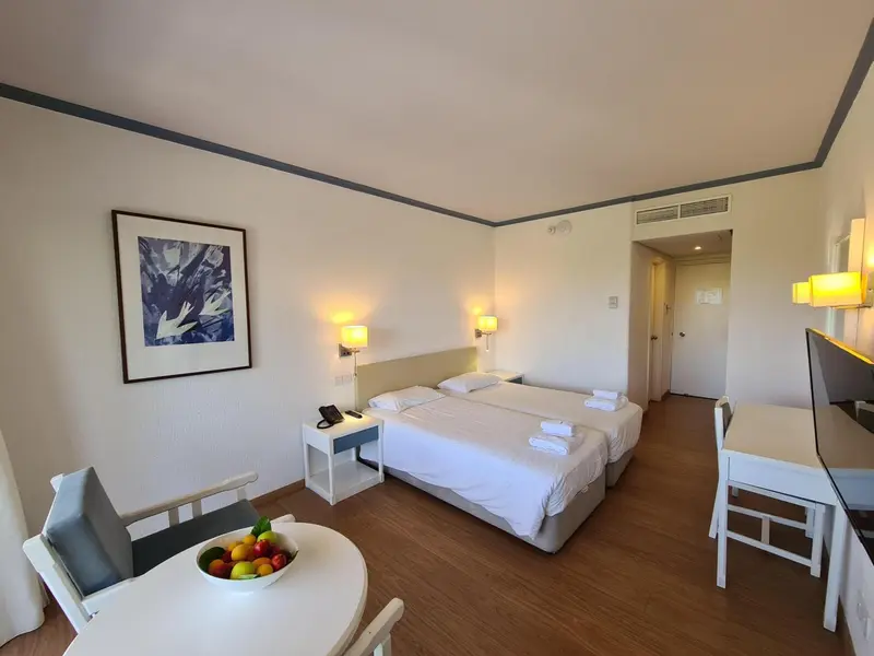 Chambre lumineuse avec deux lits simples et un coin repas.