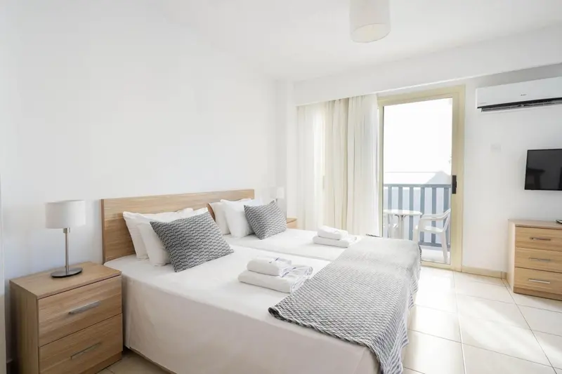Une chambre lumineuse avec un grand lit et un accès à un balcon.