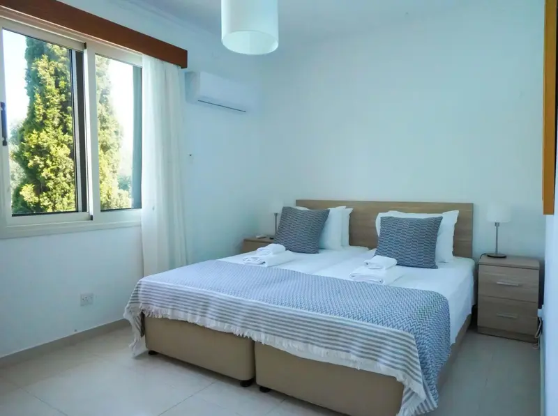 Une chambre lumineuse avec un grand lit et une vue sur la végétation.