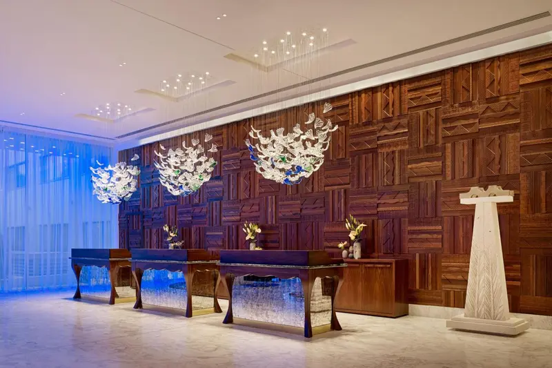 Un comptoir d'accueil moderne avec un mur décoratif en bois et des lustres lumineux.