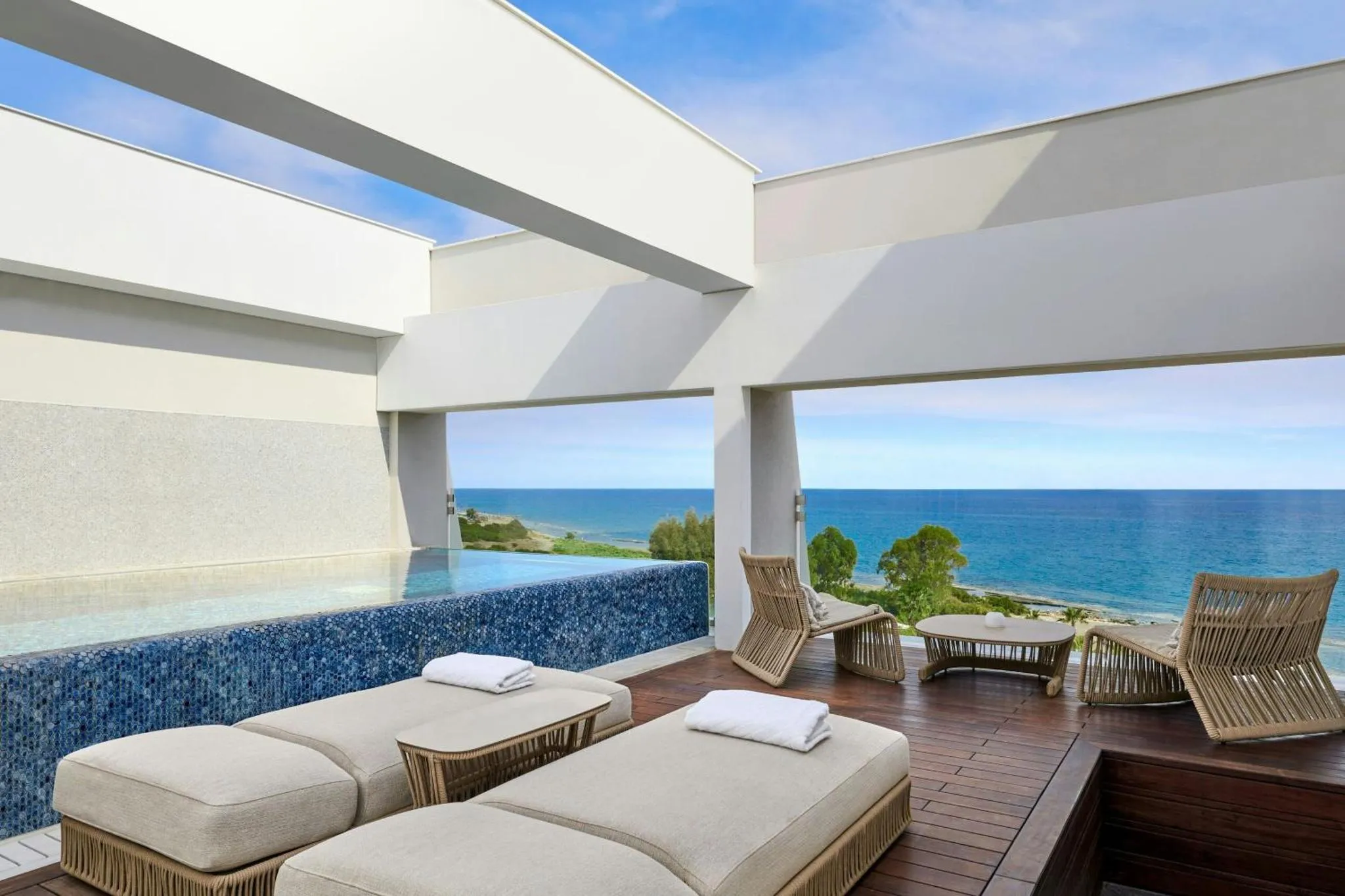 Terrasse avec transats et piscine à débordement donnant sur la mer.