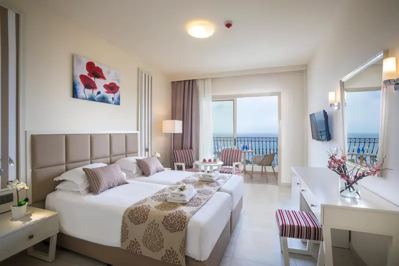 Chambre lumineuse avec lits jumeaux et vue sur la mer.