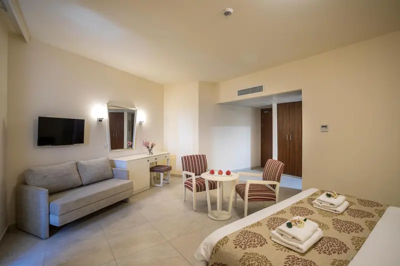 Une chambre lumineuse avec un canapé, des fauteuils et un lit soigné.