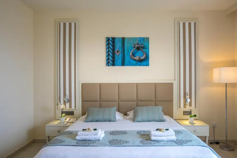 Une chambre lumineuse avec un grand lit et une décoration murale abstraite.