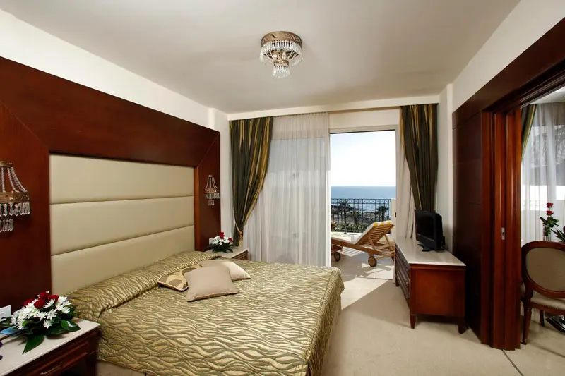Chambre avec un grand lit et une vue sur la mer par une baie vitrée.