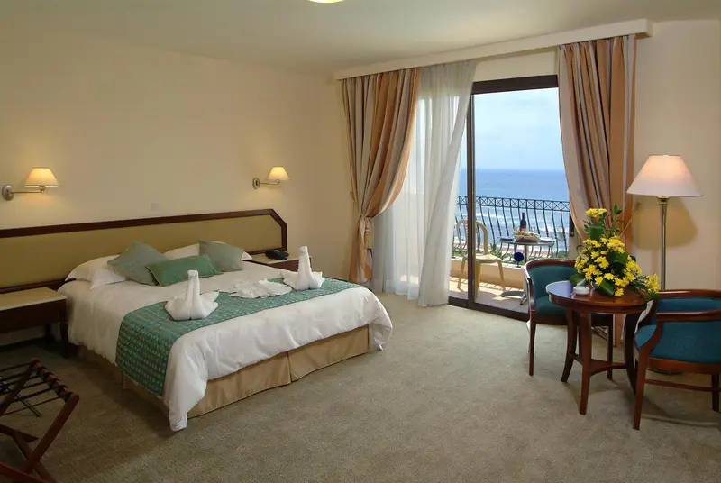 Chambre lumineuse avec un lit fait et une vue sur la mer.