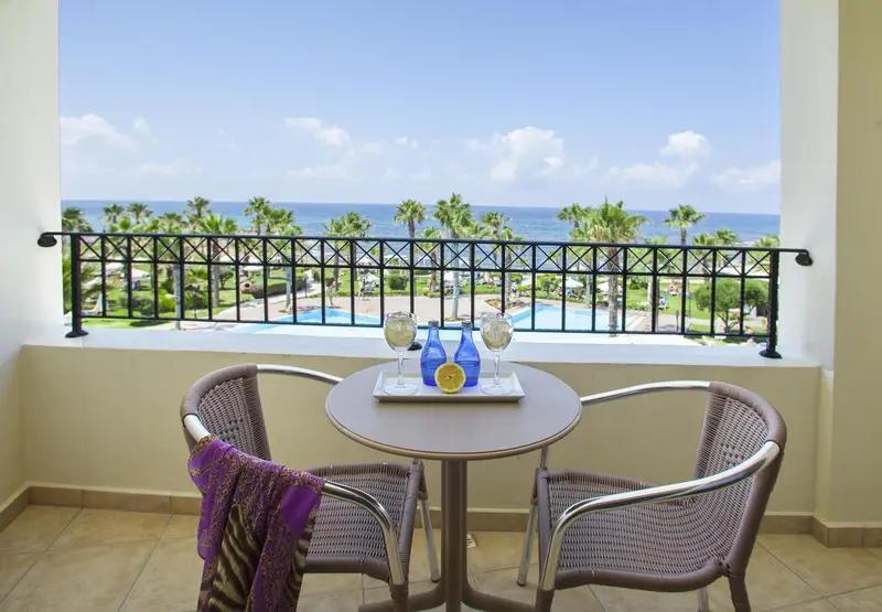 Une table ronde avec deux verres et des citrons sur une terrasse ensoleillée avec vue sur la mer.