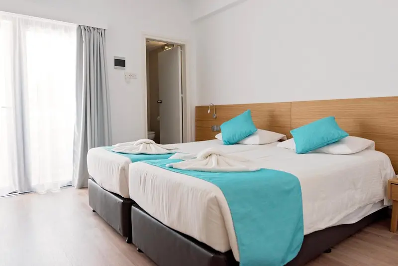Une chambre lumineuse avec deux lits simples et une décoration turquoise.