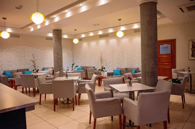 Une salle lumineuse avec des tables et des chaises est aménagée pour la restauration.