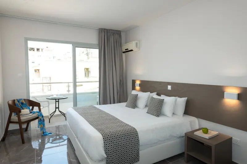 Une chambre lumineuse avec un lit double et un coin salon.