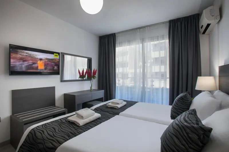 Une chambre moderne avec un lit double et une télévision murale.