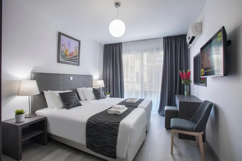Une chambre lumineuse avec un grand lit et un espace bureau.
