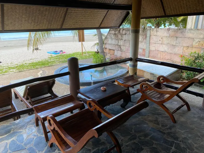 Espace de détente extérieur avec mobilier en bois et vue sur la plage.