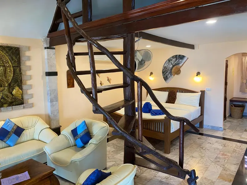 Une chambre avec un canapé, un lit et un escalier en bois.