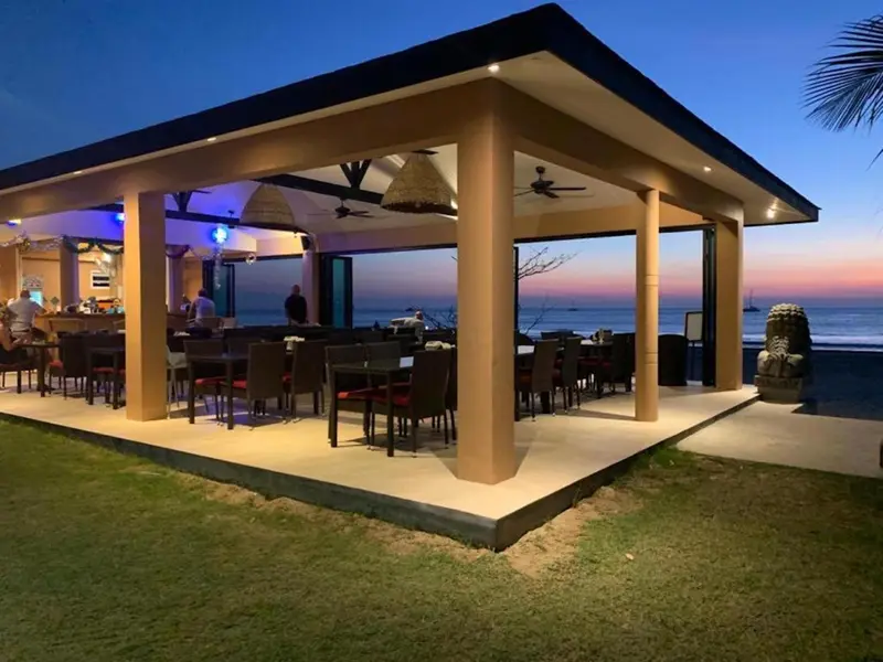 Terrasse ouverte sur la mer avec tables et comptoir de bar.