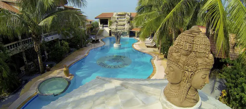 Vue aérienne d'une piscine sinueuse au sein d'un complexe hôtelier tropical.