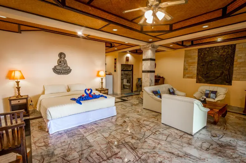 Une chambre lumineuse avec un lit décoré et un coin salon.