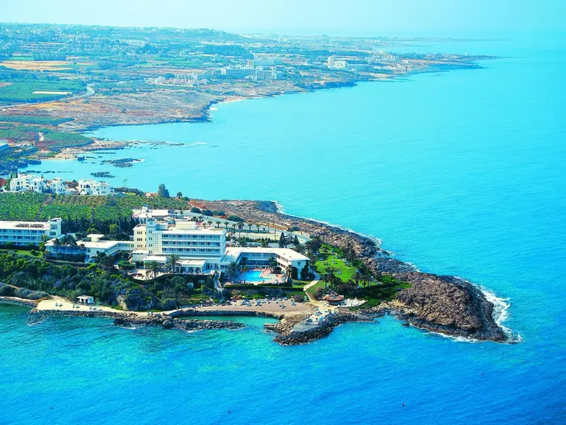 Vue aérienne d'un complexe hôtelier en bord de mer avec une plage et une piscine.
