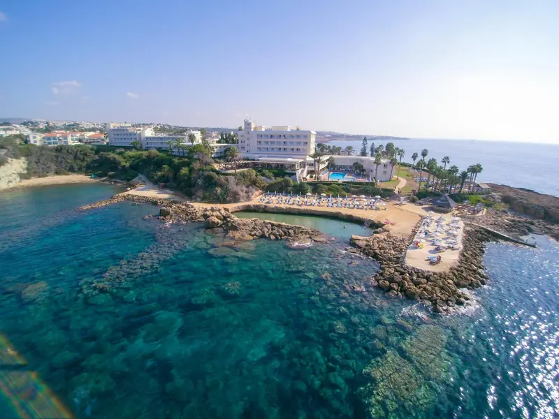 Vue aérienne d'un complexe hôtelier au bord de la mer turquoise.