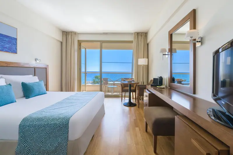 Chambre lumineuse avec un lit double et une vue sur la mer.