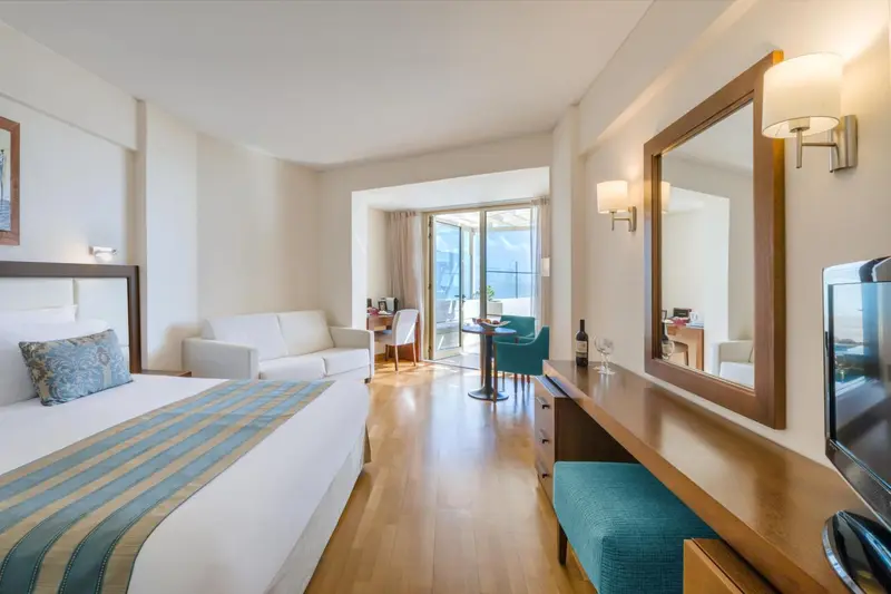 Une chambre lumineuse avec un lit, un canapé et un coin repas.