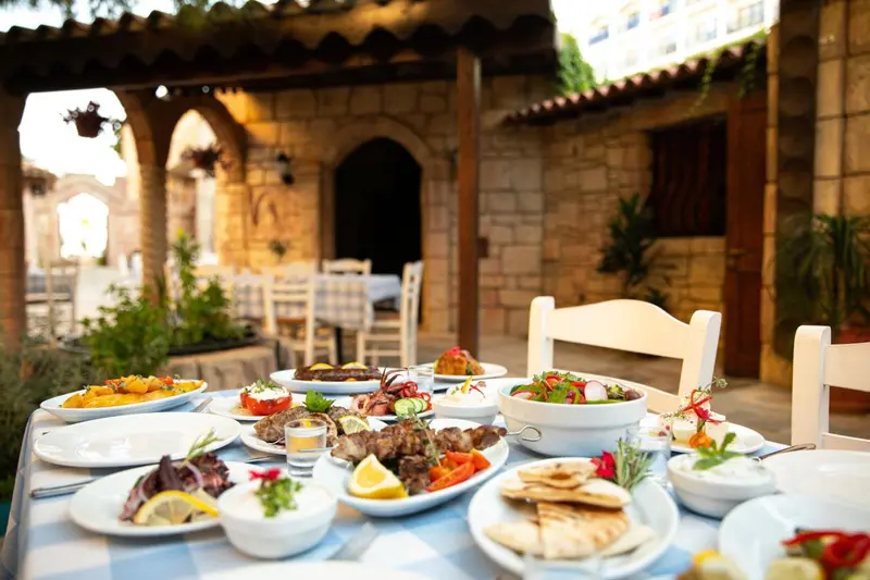 Une table dressée avec des plats variés et colorés en extérieur.