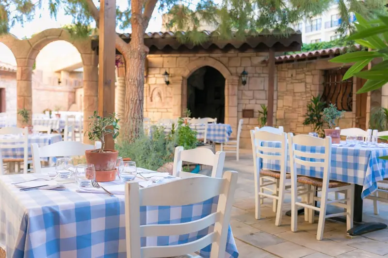 Tables dressées en extérieur sous une pergola ombragée.