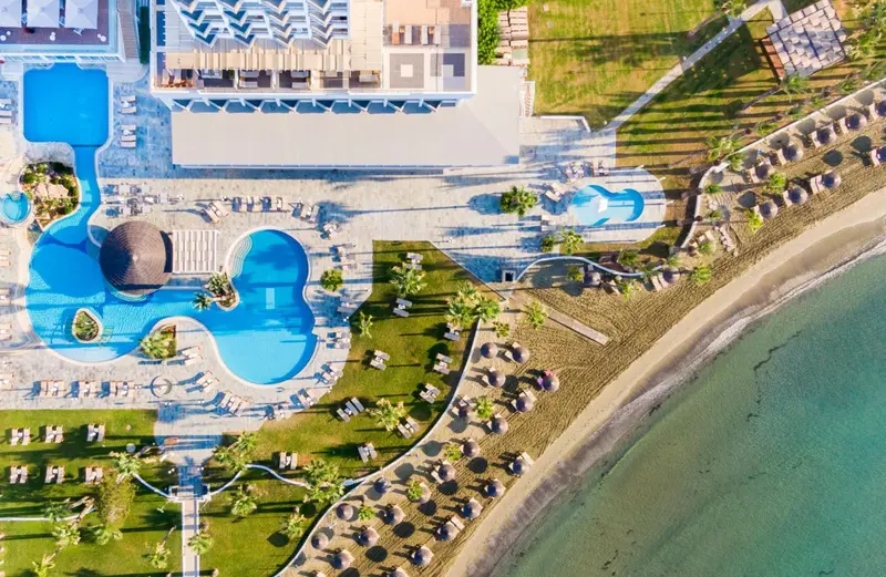 Vue aérienne d'un complexe hôtelier avec piscines et plage.
