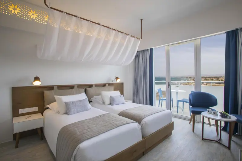 Chambre lumineuse avec un grand lit et une vue sur la mer.