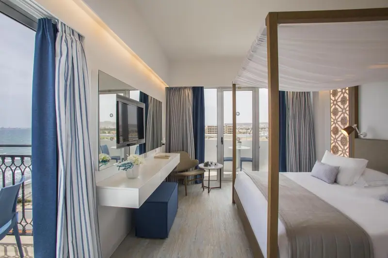 Une chambre lumineuse avec un grand lit à baldaquin et une vue sur la mer.