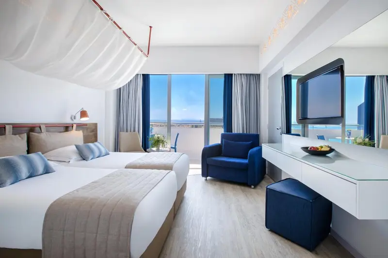 Chambre lumineuse avec lits jumeaux et vue sur la mer.