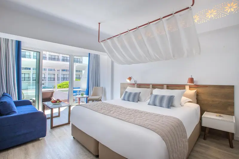 Une chambre lumineuse avec un grand lit et un canapé bleu.