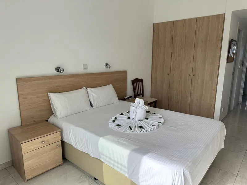 Une chambre lumineuse avec un grand lit et un meuble de rangement en bois.