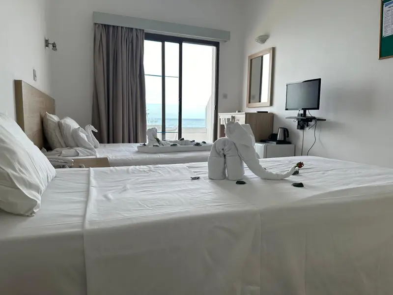 Chambre lumineuse avec deux lits simples et vue sur la mer.