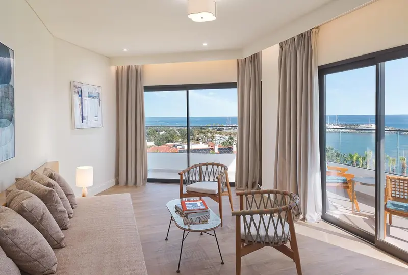 Espace de détente lumineux avec canapés et vue sur la mer.