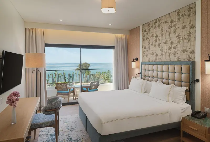 Chambre lumineuse avec un grand lit et une vue sur la mer.
