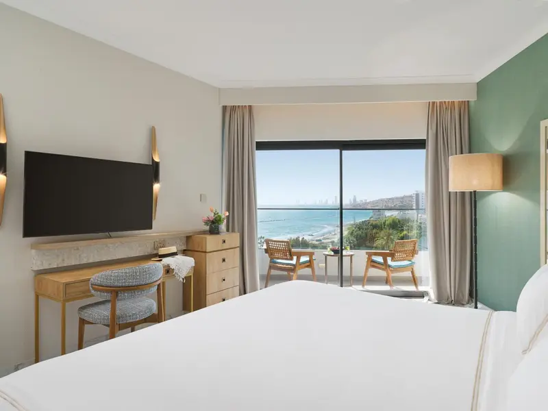 Une chambre lumineuse avec un lit blanc et une vue sur la mer.
