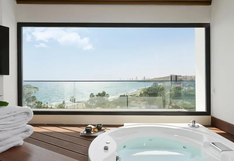 Une baignoire d'angle offre une vue dégagée sur la mer et la côte.
