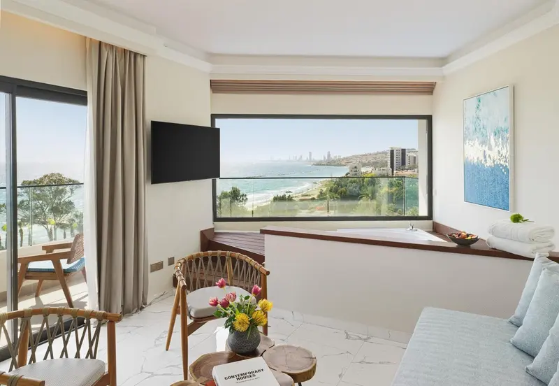 Une chambre lumineuse avec un coin salon et vue sur la mer.