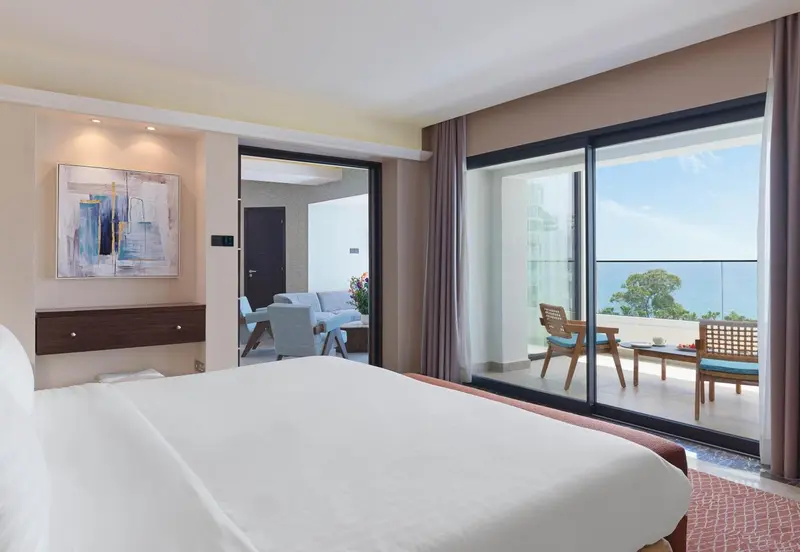 Une chambre lumineuse s'ouvre sur une terrasse avec vue sur la mer.