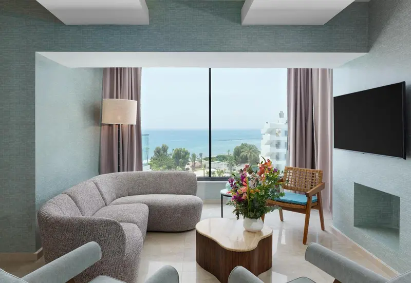 Un salon lumineux avec un canapé incurvé et une vue sur la mer.