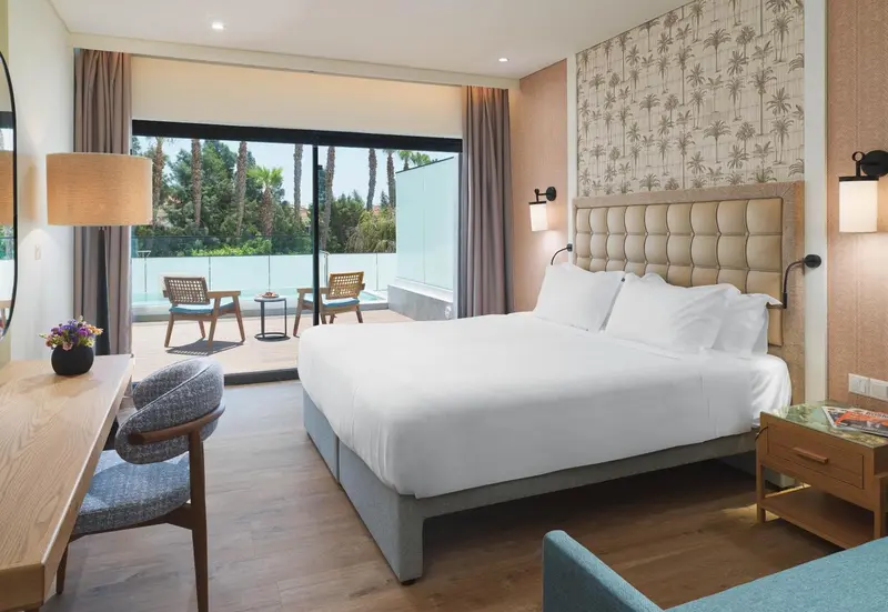 Une chambre lumineuse avec un grand lit et un accès à une terrasse.