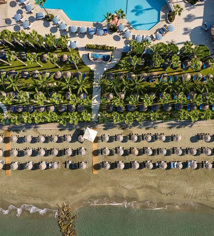 Vue aérienne d'une plage avec des transats alignés et une piscine.