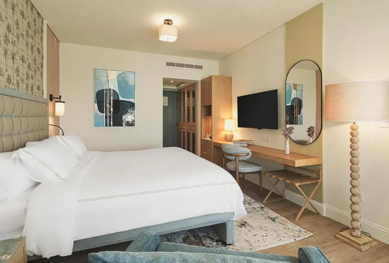 Une chambre lumineuse avec un grand lit et un espace bureau.