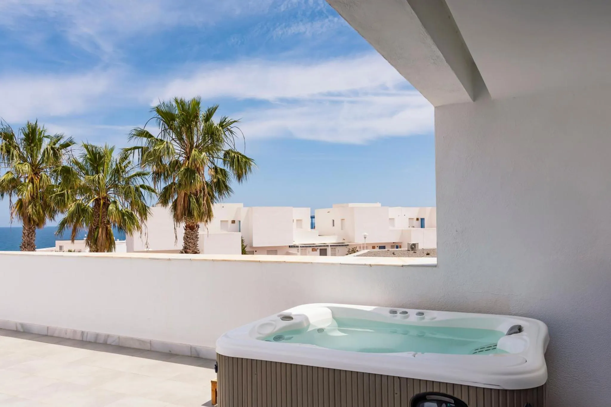 Terrasse avec jacuzzi et vue sur la mer et la végétation.