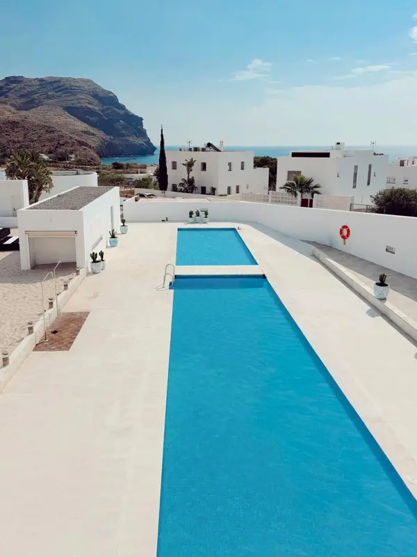 Vue aérienne d'une piscine rectangulaire devant un bâtiment blanc.