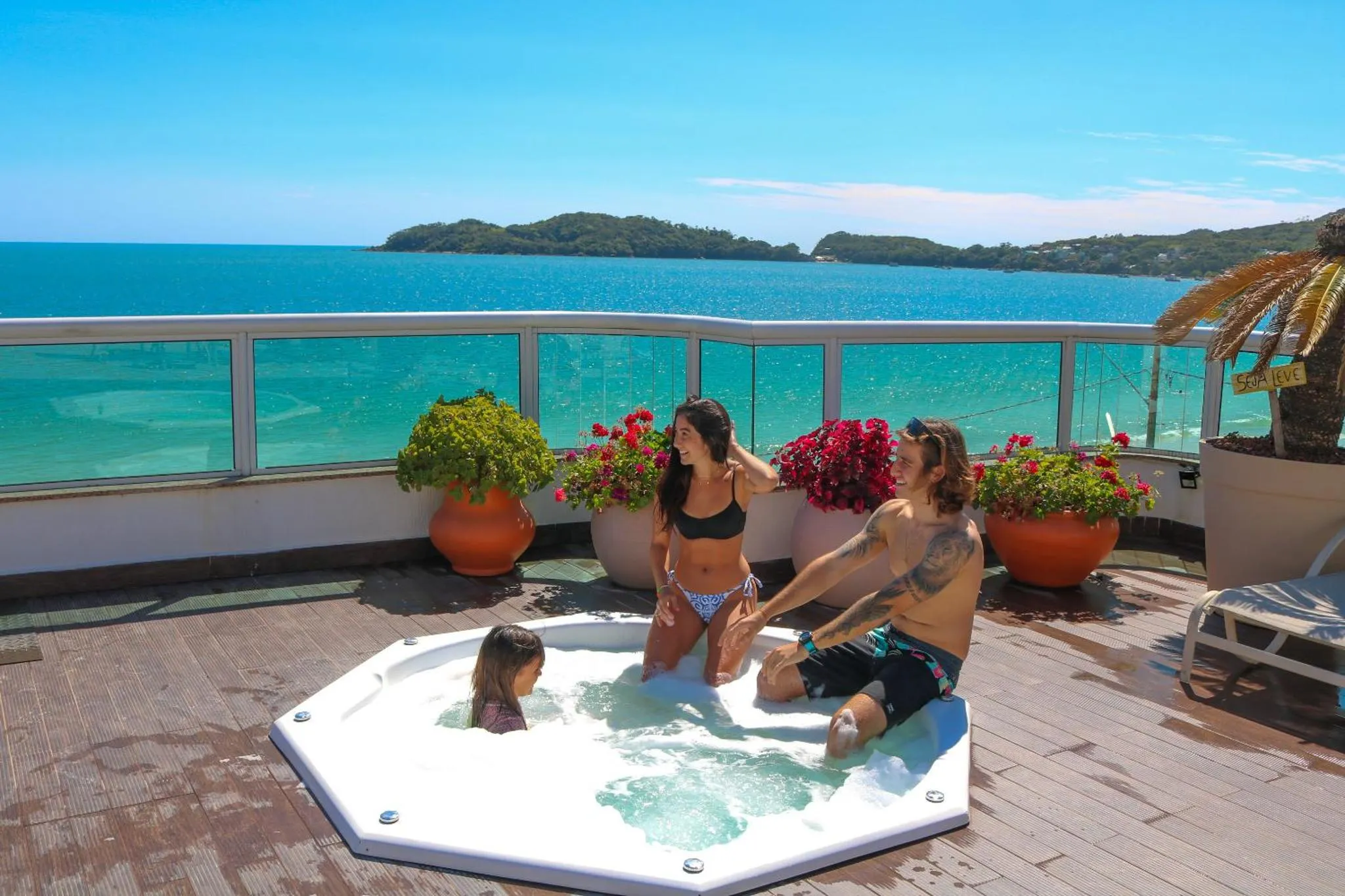 Une terrasse avec un jacuzzi et des personnes se détendant face à la mer.