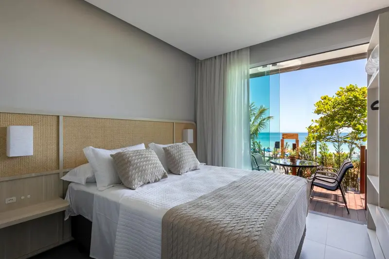 Chambre lumineuse avec un grand lit et une vue sur la mer.