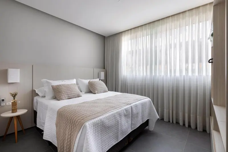 Une chambre lumineuse avec un grand lit recouvert d'une courtepointe.
