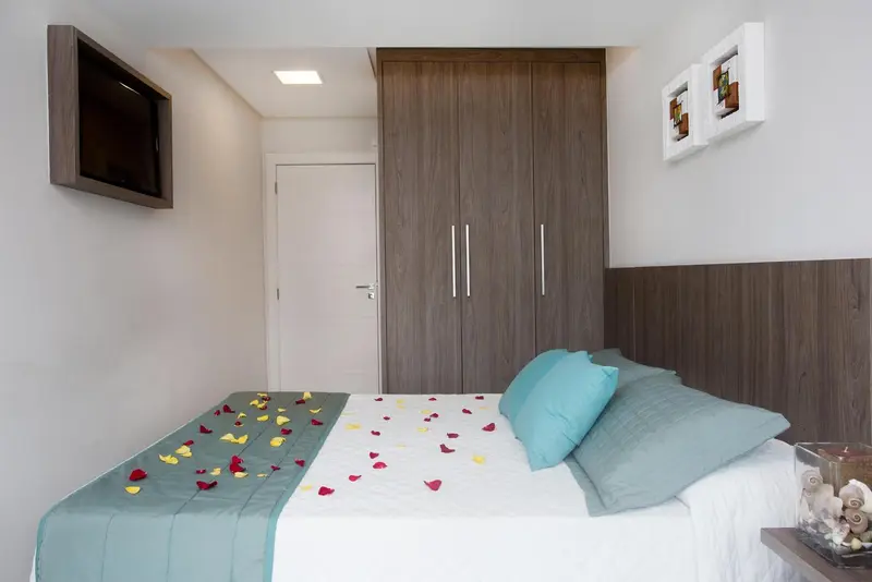 Une chambre avec un lit décoré de pétales et un téléviseur mural.